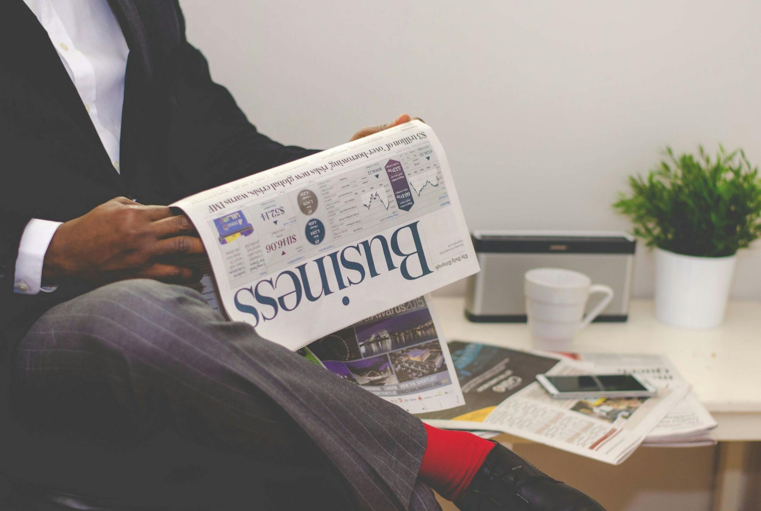 Photo by nappy Businessman reading a financial newspaper at a desk, highlighting finance and commerce theme.