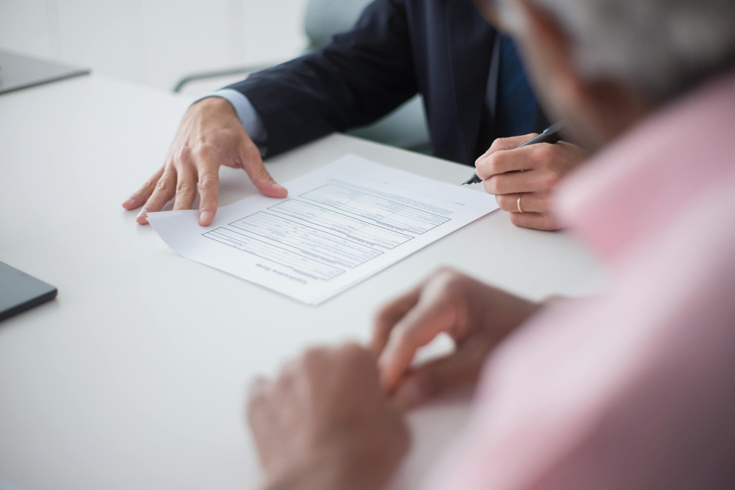 Photo by Kampus Production Two professionals engaging in a business meeting, signing documents for a consulting agreement.